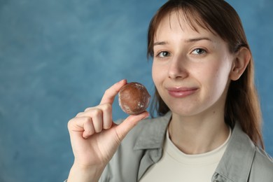 Photo of Beautiful woman with tasty mochi on blurred blue background. Space for text