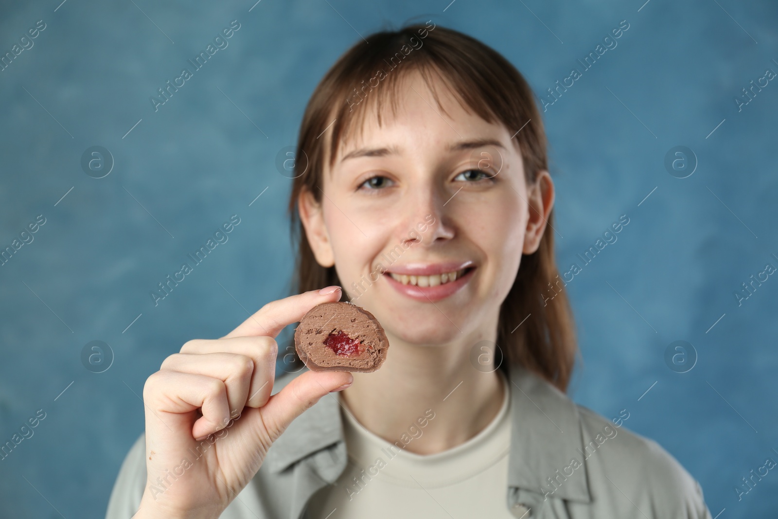 Photo of Smiling woman with tasty mochi on blurred blue background