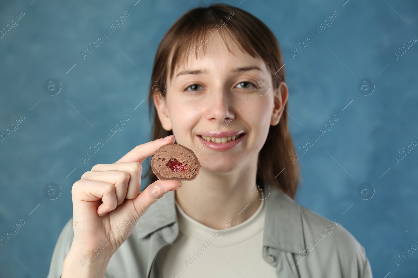 Photo of Smiling woman with tasty mochi on blurred blue background