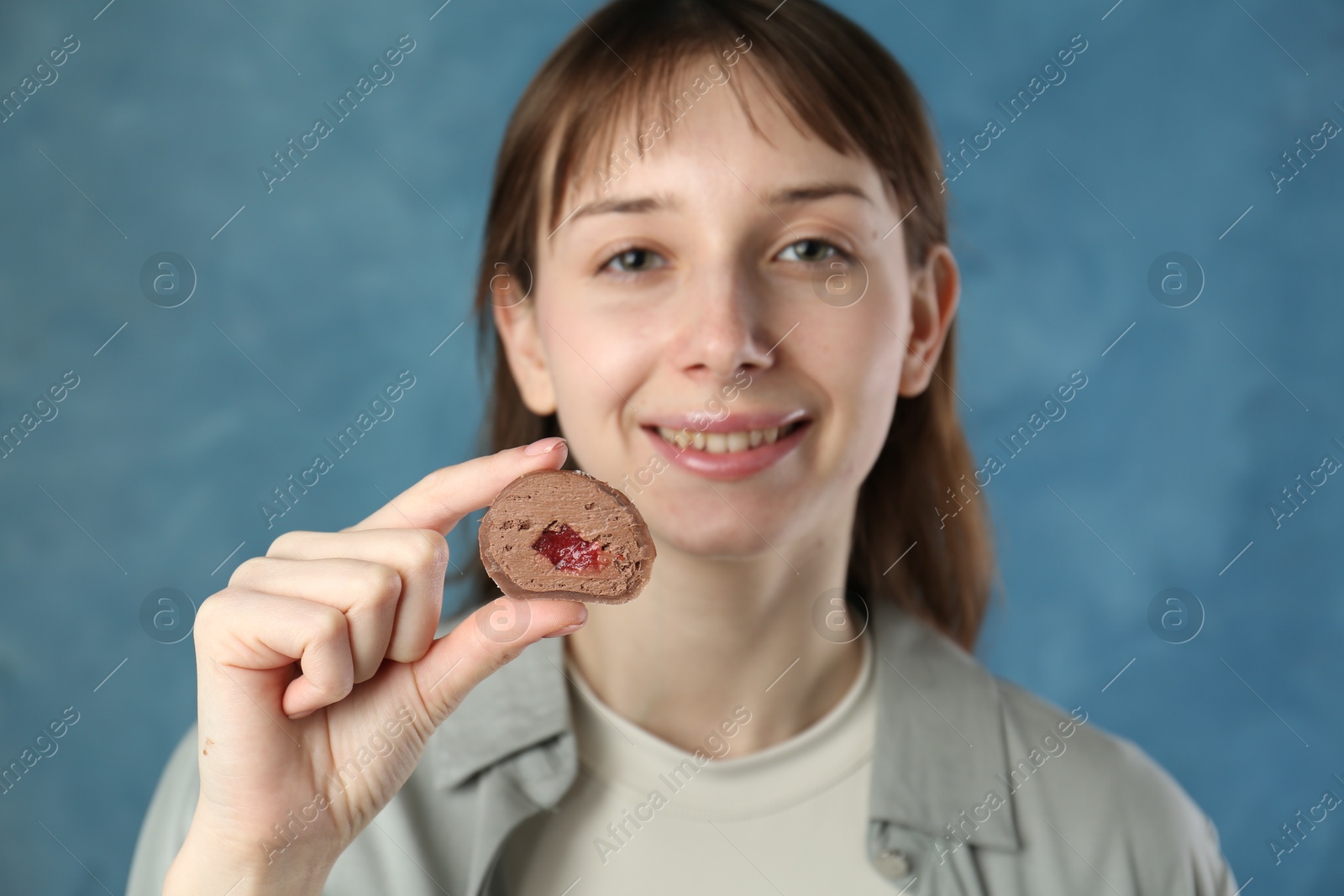 Photo of Smiling woman with tasty mochi on blurred blue background