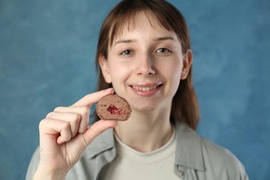 Photo of Smiling woman with tasty mochi on blurred blue background