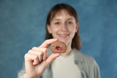 Photo of Smiling woman with tasty mochi on blurred blue background, selective focus