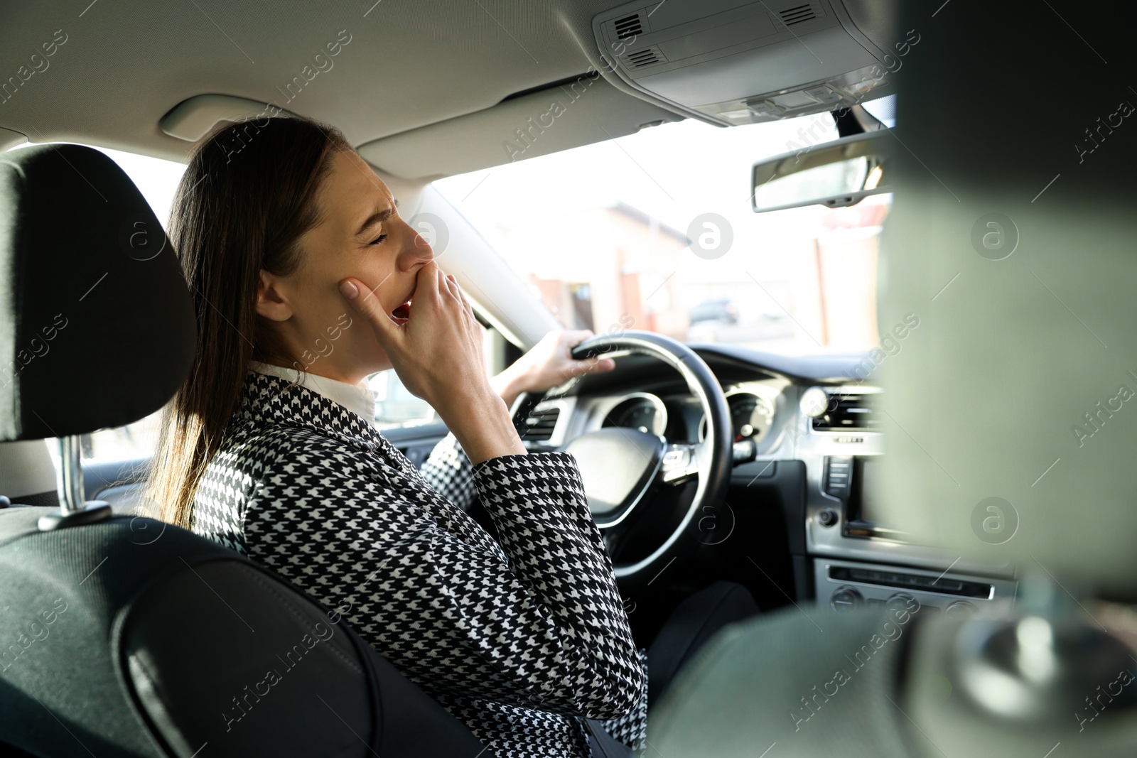 Photo of Sleepy driver yawning in her modern car, view from inside