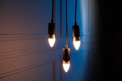 Photo of Glowing light bulbs hanging near wall indoors