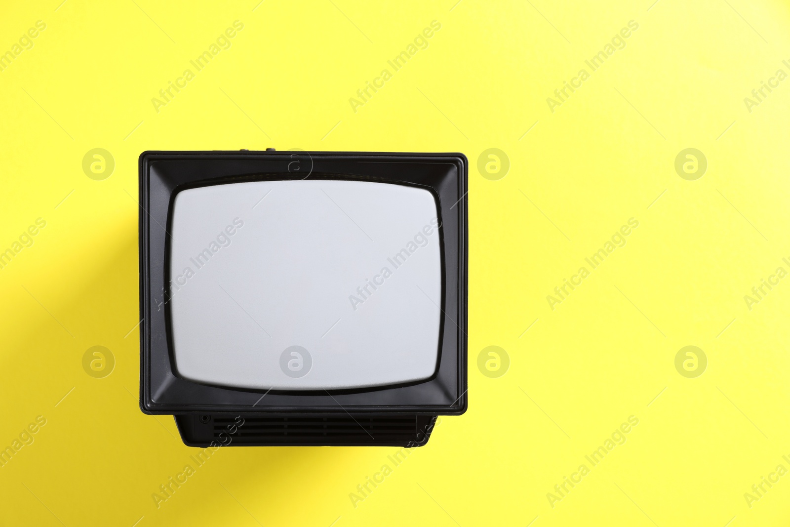 Photo of Retro tv set on yellow background, top view. Space for text