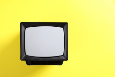 Photo of Retro tv set on yellow background, top view. Space for text