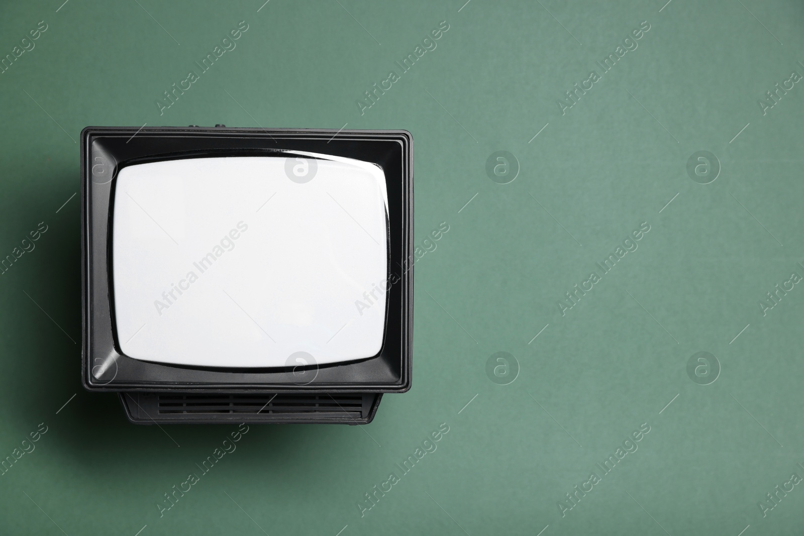 Photo of Retro tv set on green background, top view. Space for text