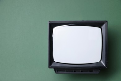 Photo of Retro tv set on green background, top view. Space for text