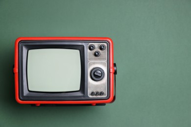 Photo of Retro tv set on green background, top view. Space for text