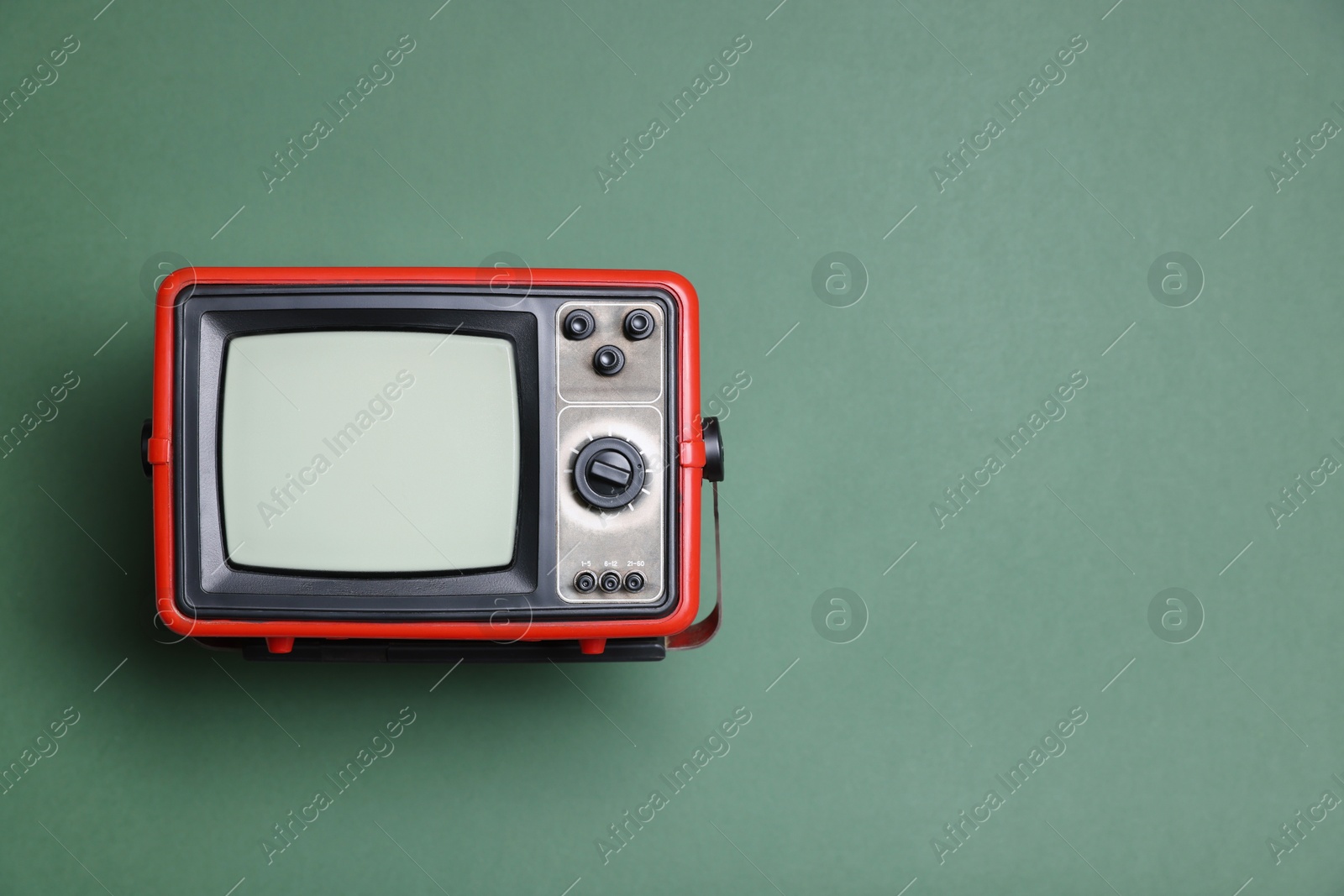 Photo of Retro tv set on green background, top view. Space for text