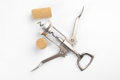 Photo of Wing corkscrew and corks on white background, top view