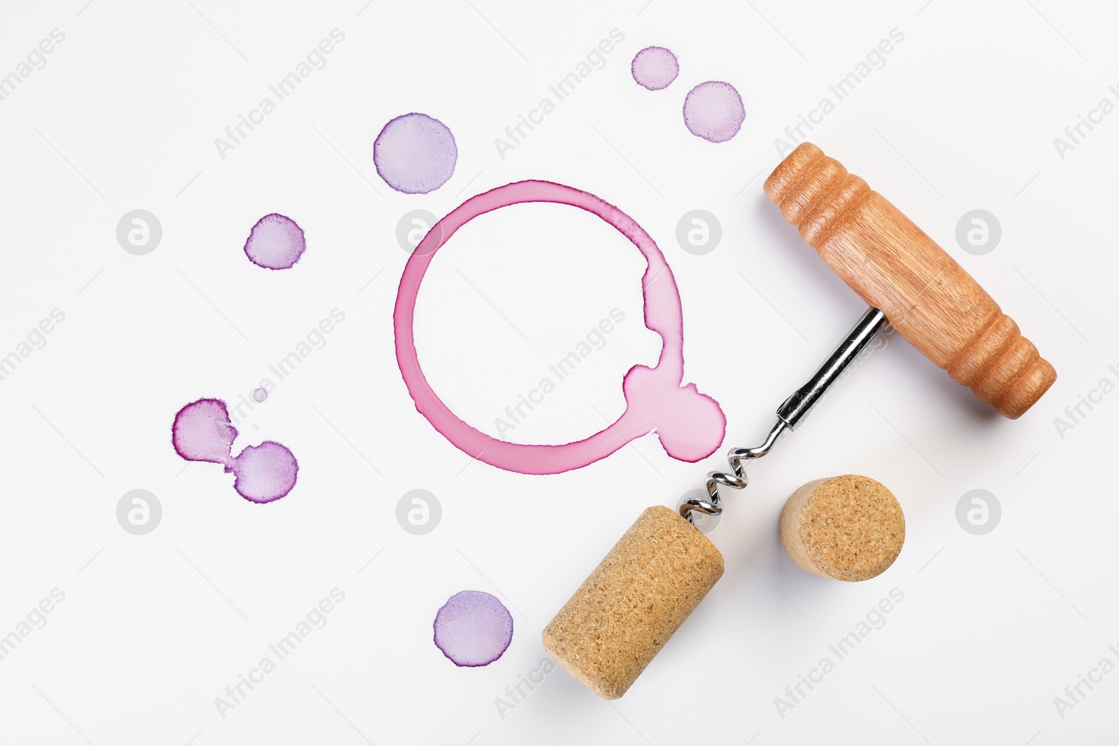 Photo of Corkscrew, cork and red wine stains on white background, top view