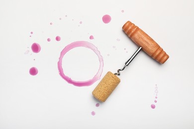 Photo of Corkscrew, cork and red wine stains on white background, top view