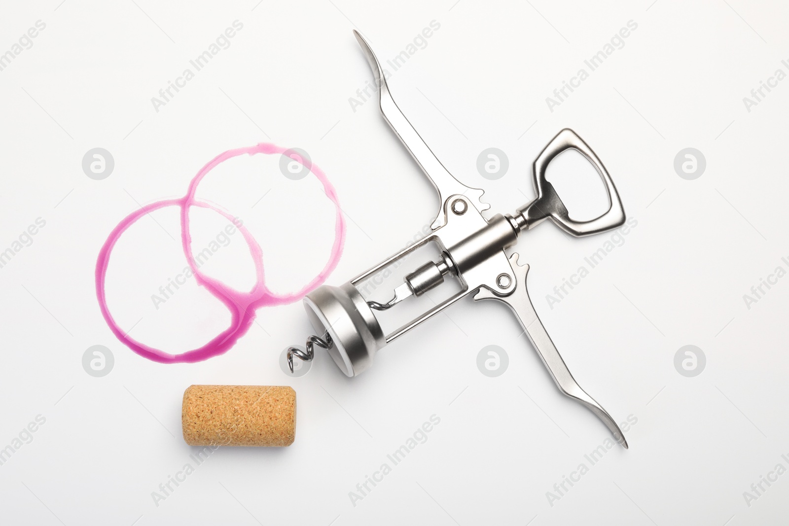 Photo of Wing corkscrew, cork and red wine stains on white background, top view