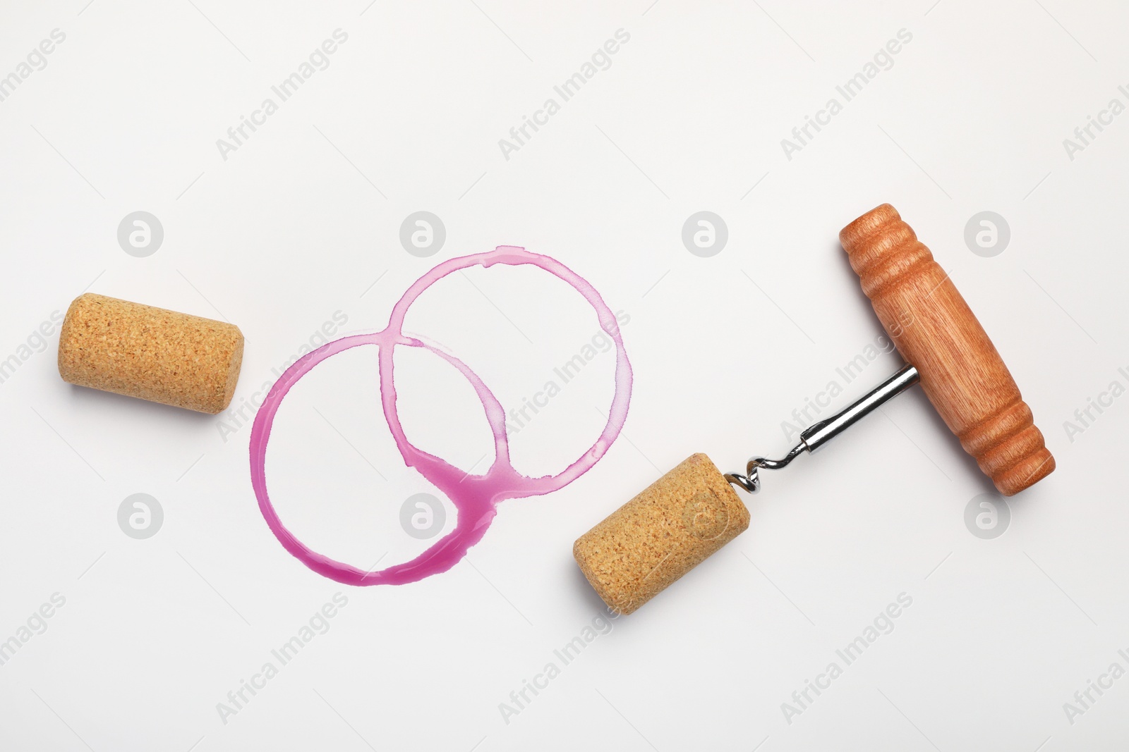 Photo of Corkscrew, corks and red wine stains on white background, top view