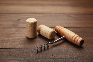 Photo of Corkscrew with handle and corks on wooden table