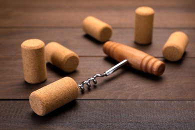 Photo of Corkscrew with handle and corks on wooden table