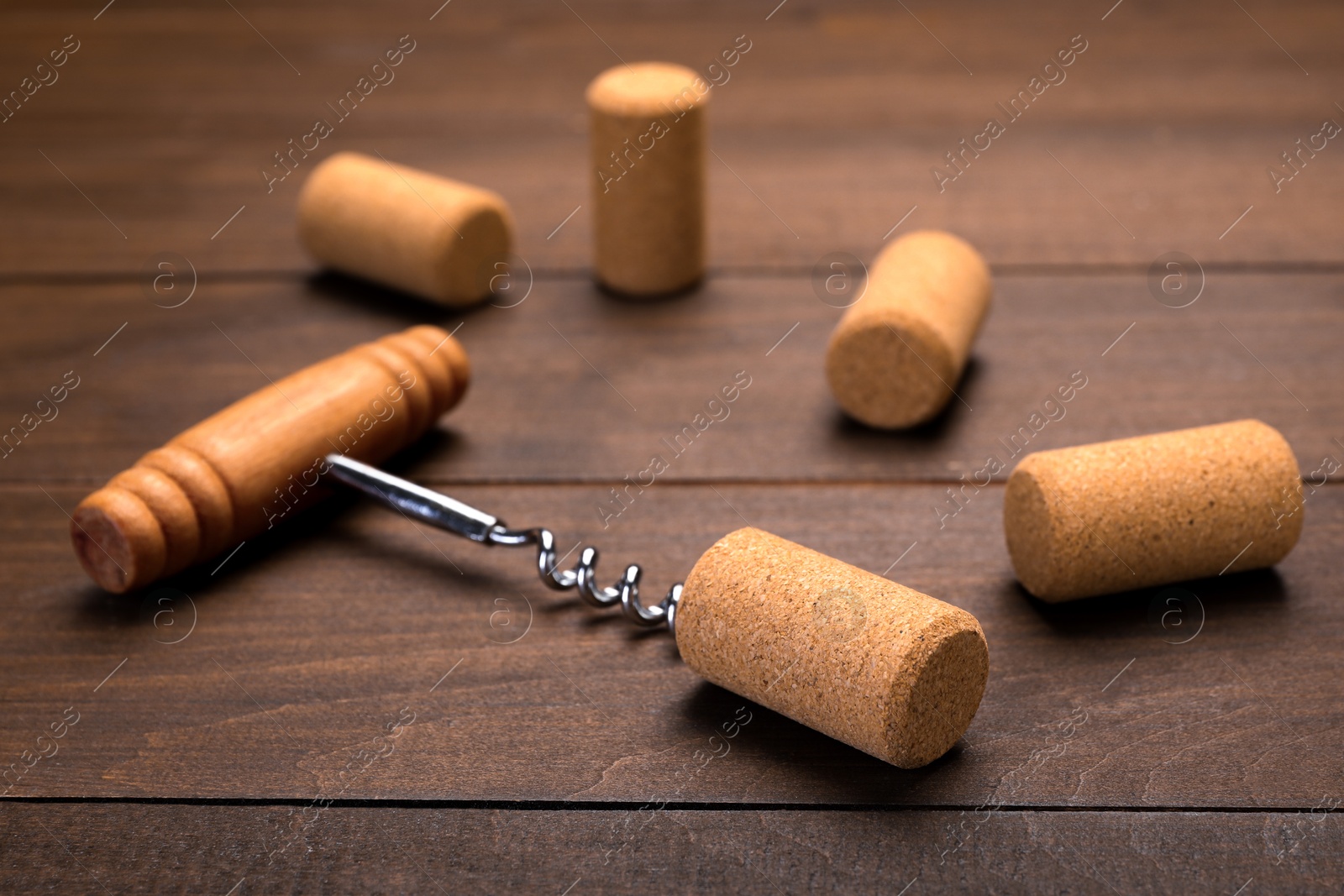 Photo of Corkscrew with handle and corks on wooden table