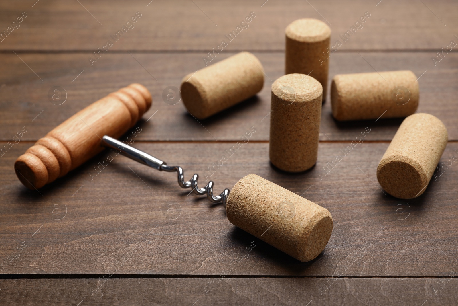 Photo of Corkscrew with handle and corks on wooden table