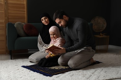 Photo of Muslim family with Quran praying on mat at home