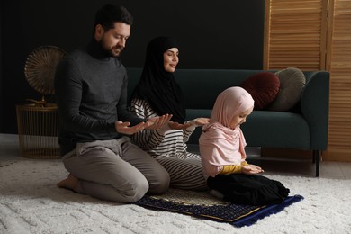 Photo of Muslim family praying on mat at home