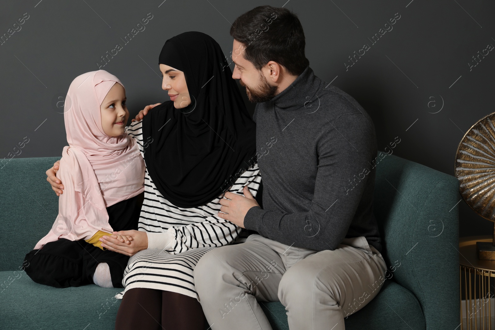 Photo of Happy Muslim family sitting on sofa at home