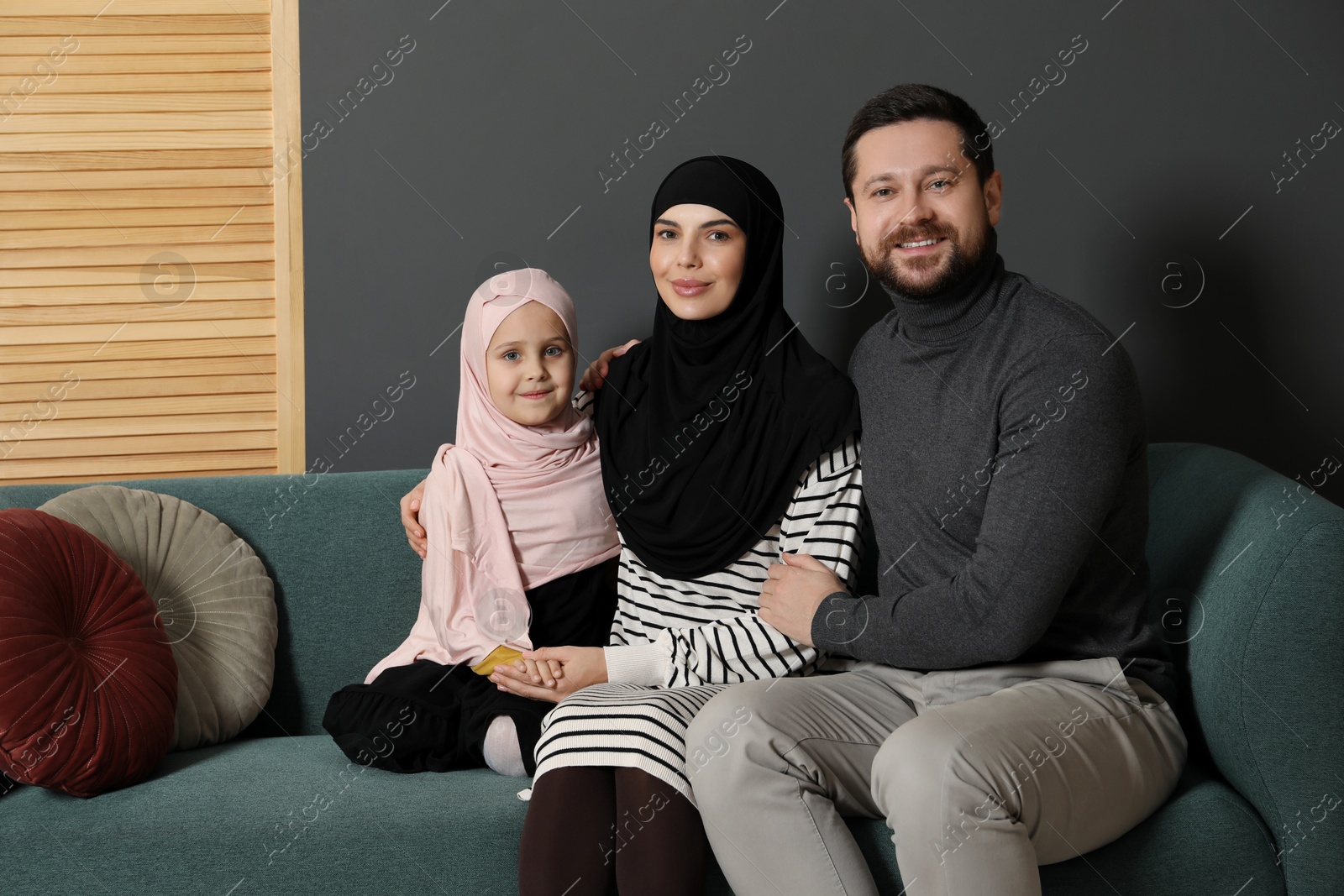 Photo of Happy Muslim family sitting on sofa at home