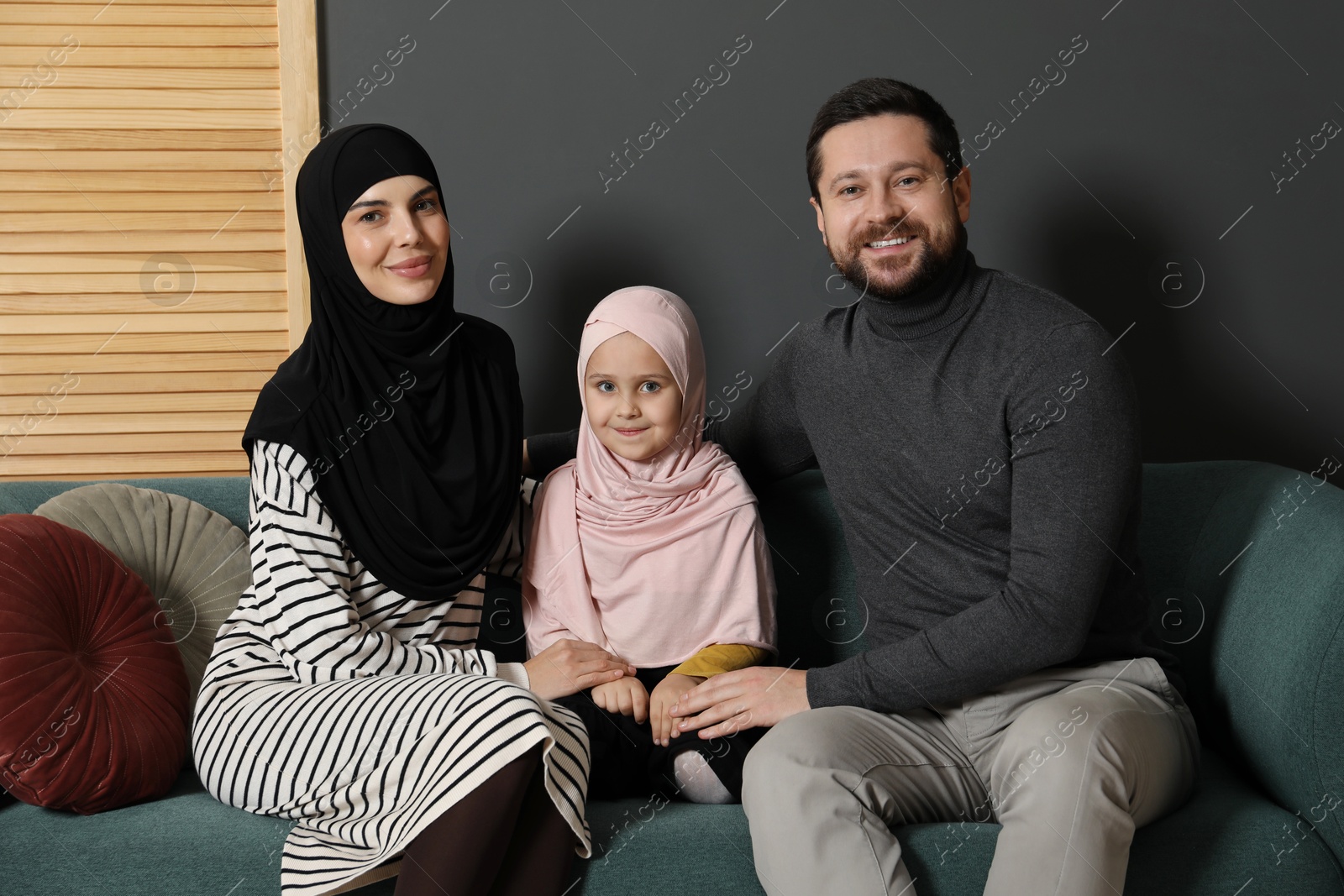 Photo of Happy Muslim family sitting on sofa at home