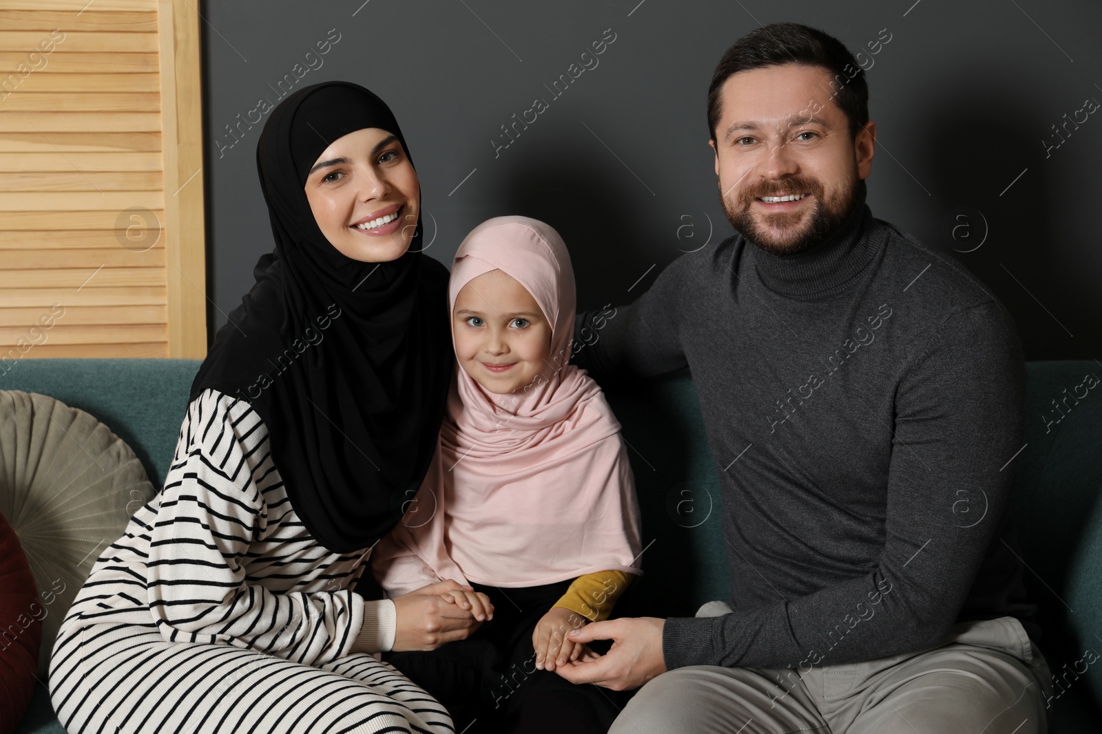 Photo of Happy Muslim family sitting on sofa at home