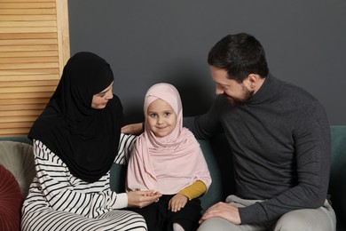 Photo of Happy Muslim family sitting on sofa at home