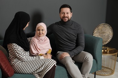 Photo of Happy Muslim family sitting on sofa at home