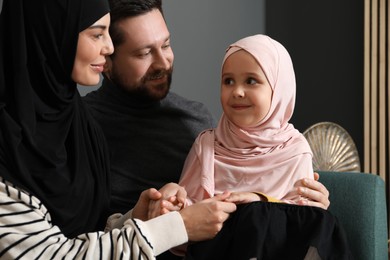 Photo of Happy Muslim family sitting on sofa at home