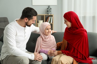 Photo of Happy Muslim family sitting on sofa at home