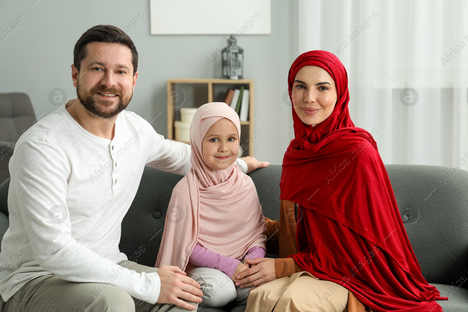 Photo of Happy Muslim family sitting on sofa at home