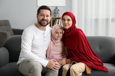 Photo of Happy Muslim family sitting on sofa at home