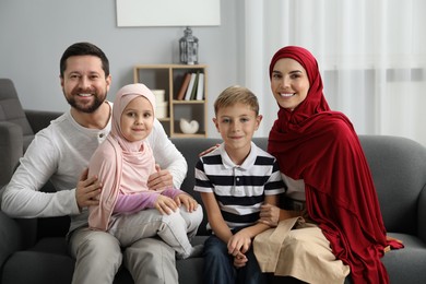 Photo of Happy Muslim family sitting on sofa at home