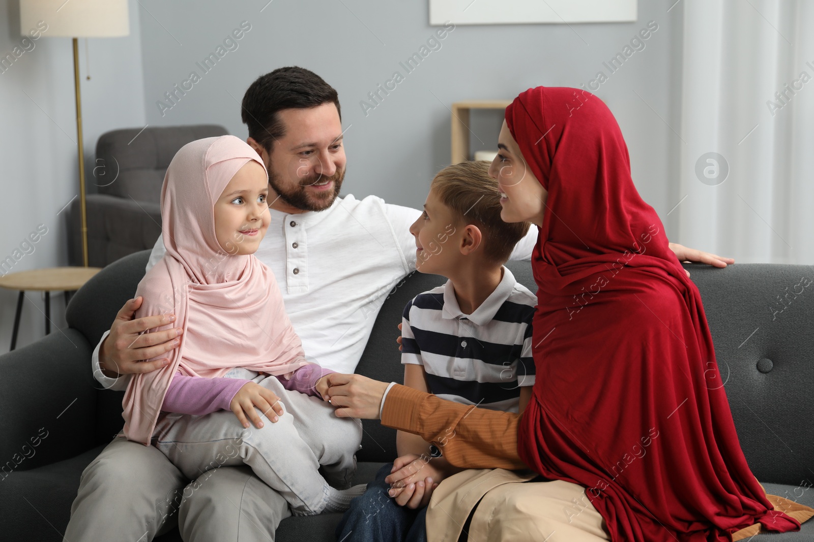 Photo of Happy Muslim family sitting on sofa at home