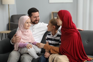 Photo of Happy Muslim family sitting on sofa at home