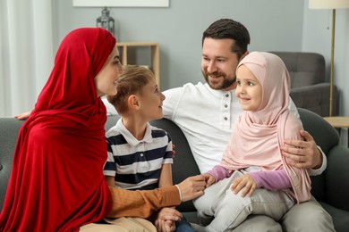 Photo of Happy Muslim family sitting on sofa at home