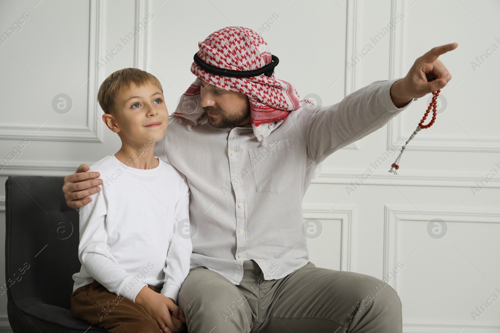 Photo of Muslim man and his son spending time together at home