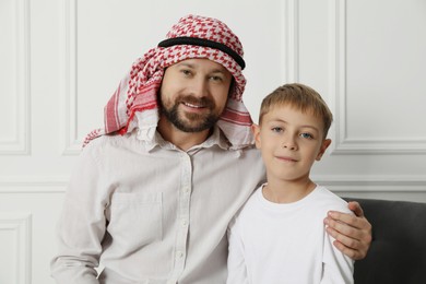 Photo of Muslim man and his son spending time together at home