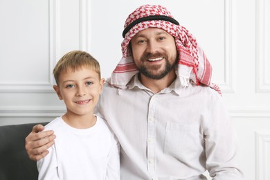 Photo of Muslim man and his son spending time together at home