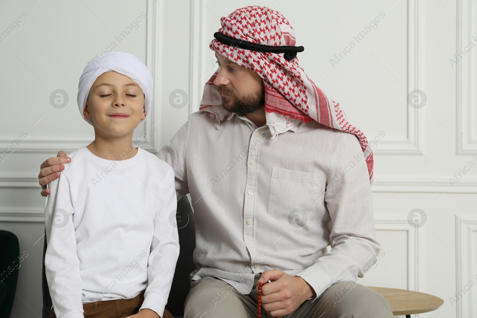 Photo of Muslim man and his son spending time together at home