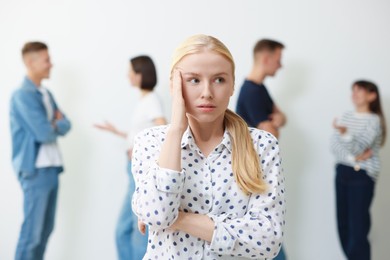 Photo of Young woman feeling uncomfortable among people indoors, selective focus