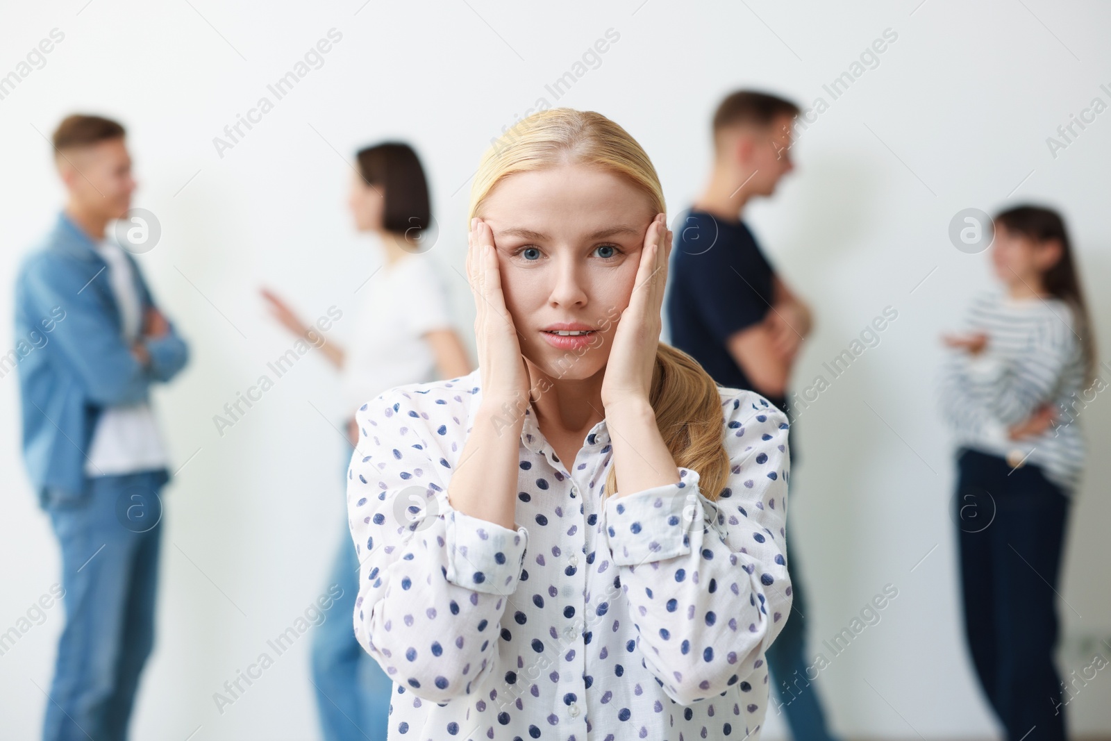 Photo of Young woman feeling uncomfortable among people indoors, selective focus