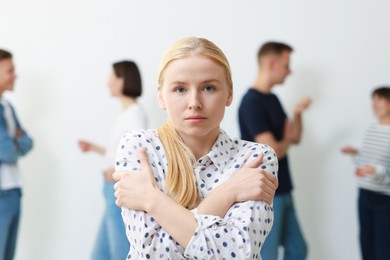 Photo of Young woman feeling uncomfortable among people indoors, selective focus