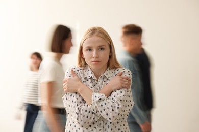 Photo of Young woman feeling uncomfortable among people indoors