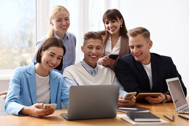 Photo of Group of people using different gadgets at wooden table in office. Modern technology