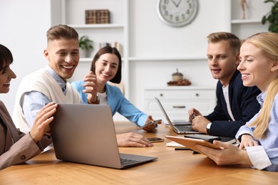 Photo of Group of people using different gadgets at wooden table in office. Modern technology