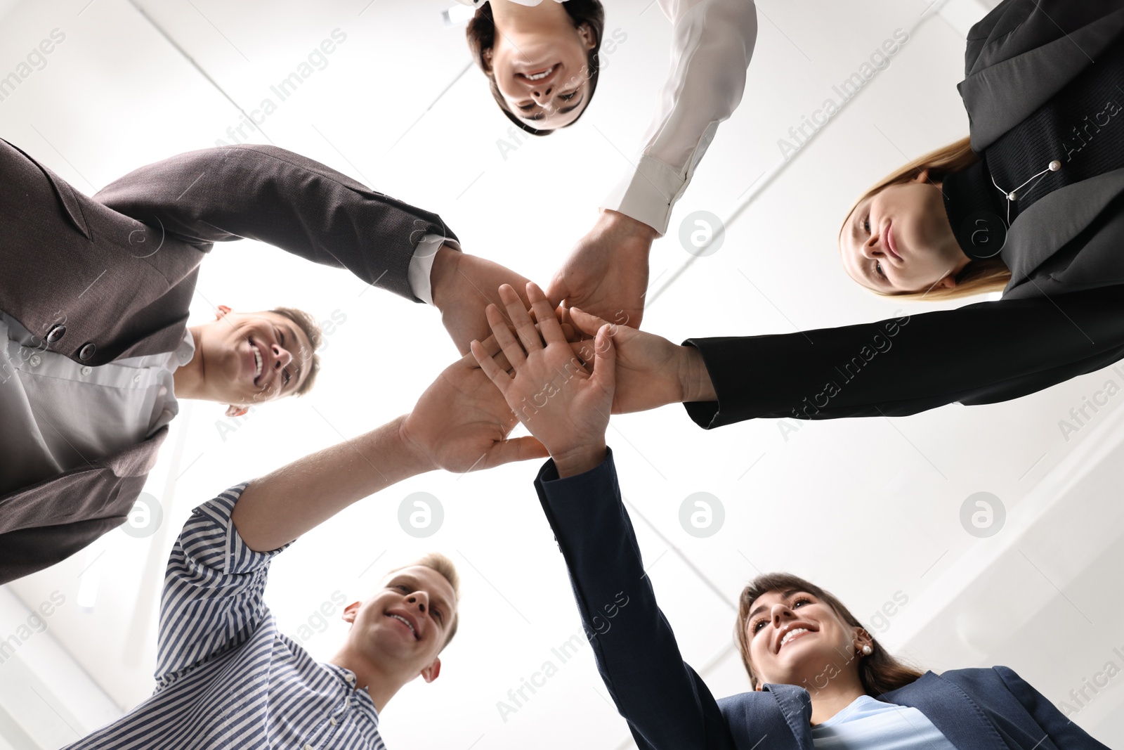 Photo of Teamwork. Group of people joining hands together indoors, bottom view